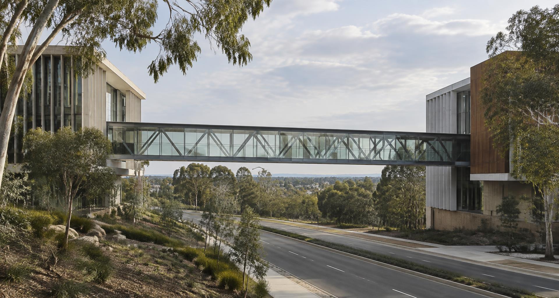 A glass pedestrian bridge linking two contemporary civic buildings